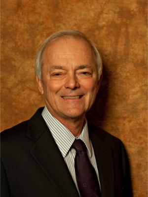 Man in suite and tie, smiling in front of orange background