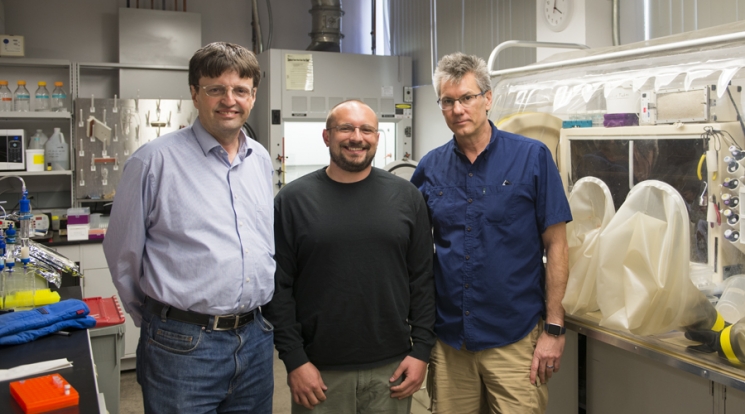Three men stand in a lab
